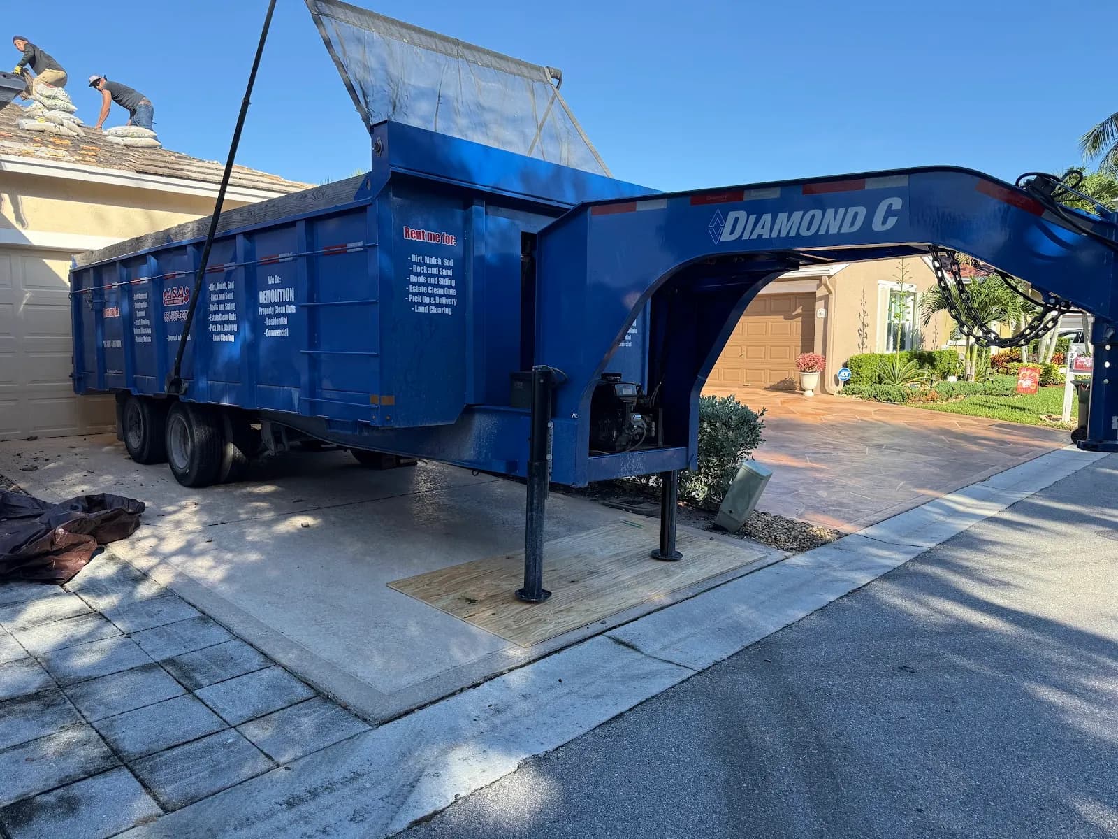 Blue Diamond C gooseneck dump trailer in a driveway with the gate open