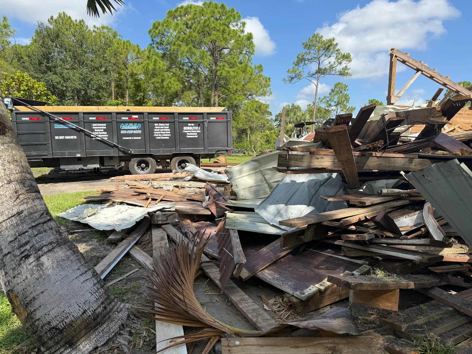 Blue dump trailer being loaded by a skid steer