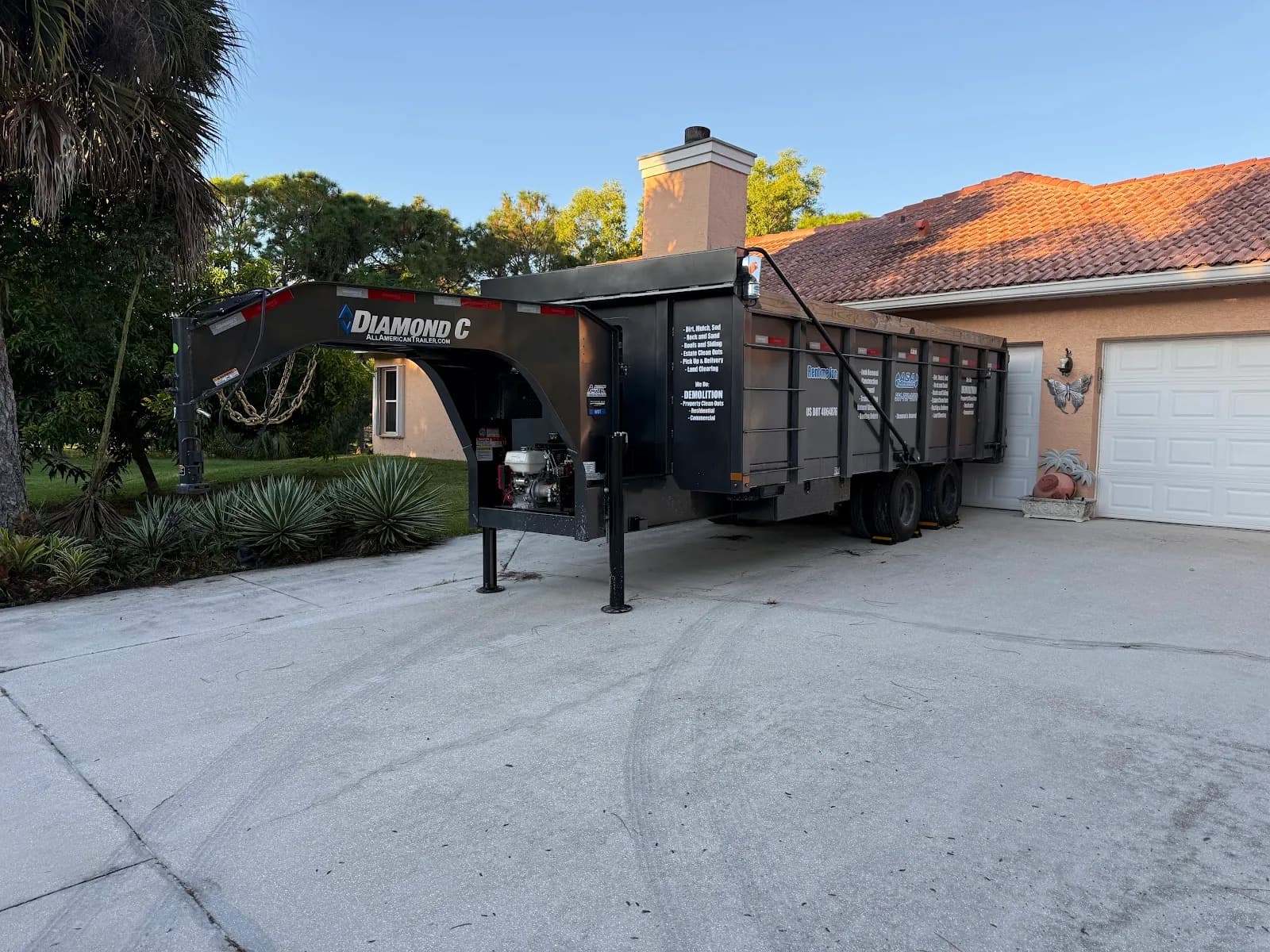 Gooseneck dump trailer in front of a tile-roof home